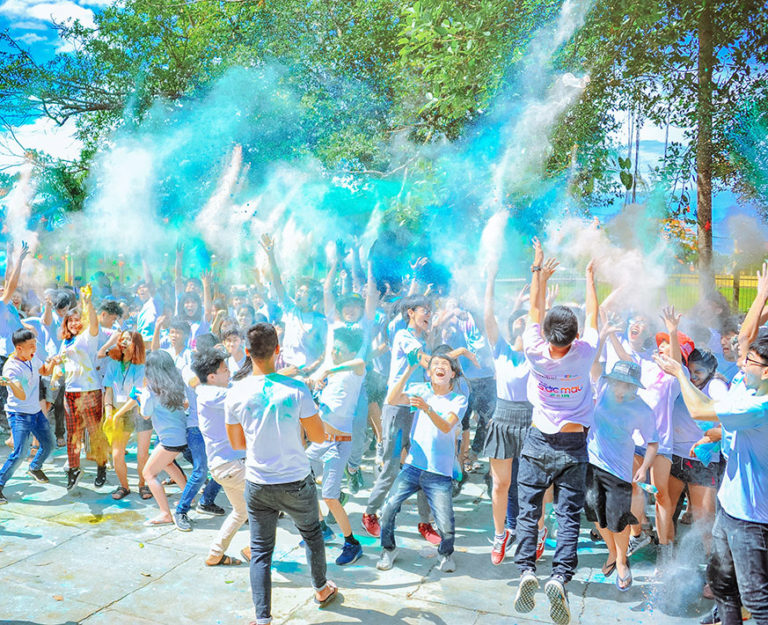 Large group of people tossing colourful chalk into the air